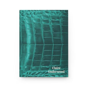 May include: A rectangular notebook with a teal-colored cover featuring a glossy, embossed crocodile skin texture. The name Claire Underwood is printed in white, sans-serif capital letters in the bottom right corner of the front cover.