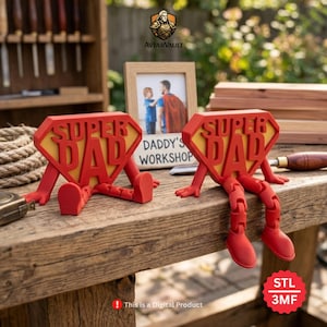 Könnte beinhalten: Zwei rote 3D-gedruckte "Super Dad" Figuren mit gelben rautenförmigen Hintergründen, die auf einer Holzoberfläche sitzen. Die Figuren haben bewegliche Beine und Arme. Ein gerahmtes Foto und der Text "Daddy's Workshop" sind im Hintergrund zu sehen. Der Text "STL 3MF" ist ebenfalls vorhanden.