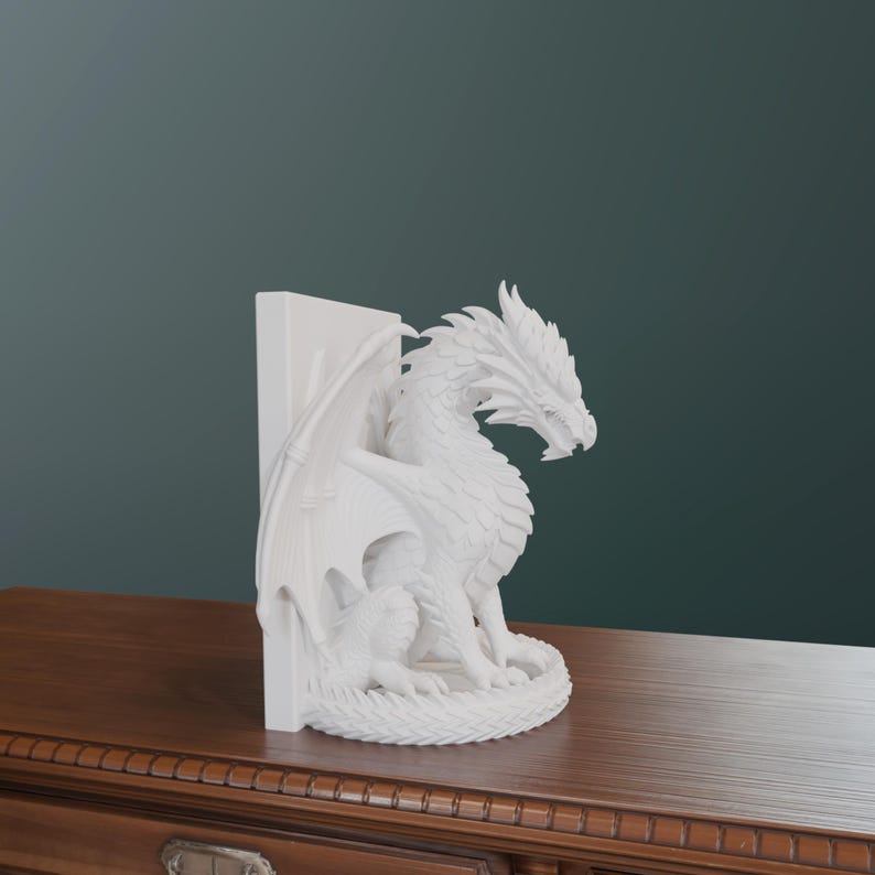Op de afbeelding: Een witte drakenboekensteun. De draak zit met uitgespreide vleugels naast een verticale steun. De sculptuur heeft gedetailleerde schubben en een felle uitdrukking. De boekensteun staat op een houten oppervlak.