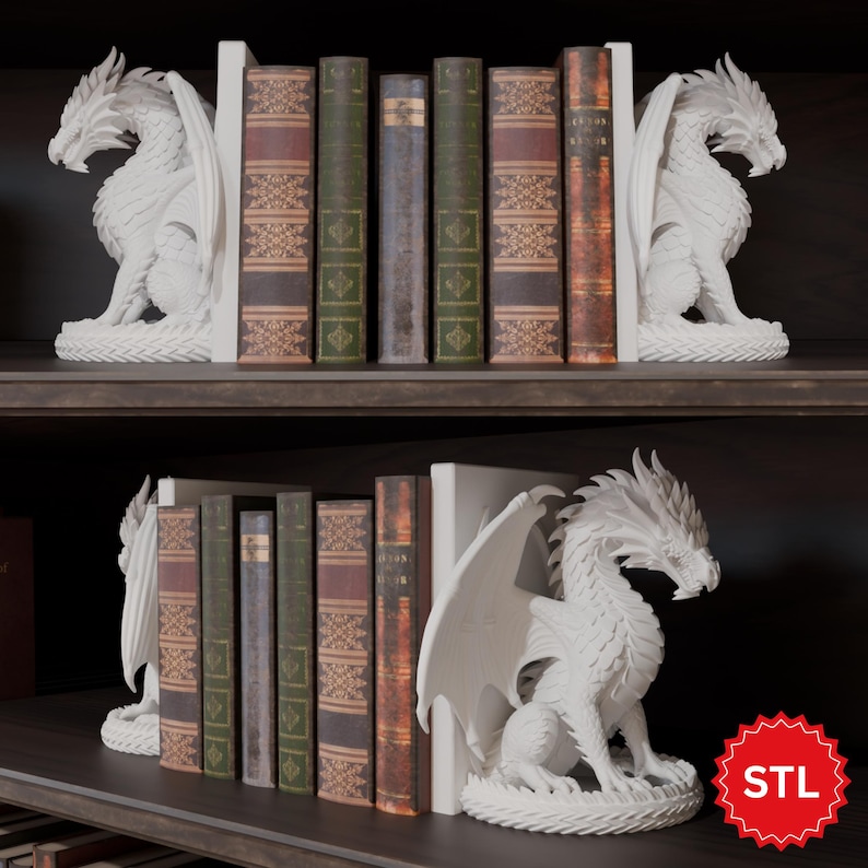 Op de afbeelding: Witte drakenboekensteunen flankeren een rij vintage boeken op een donkere plank. De drakenbeelden hebben gedetailleerde vleugels en een zittende pose. De boeken hebben verschillende kleuren en patronen, wat een klassieke stijl toevoegt.