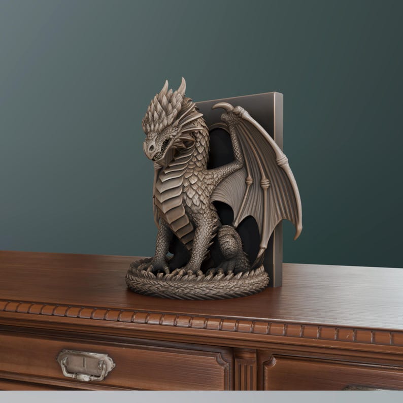 Op de afbeelding: Een bronzen drakenbeeldje met gedetailleerde schubben en vleugels. De draak zit met uitgespreide vleugels. Het is geplaatst naast een donkergrijze boekensteun, waardoor een decoratief fantasie-thema ontstaat.