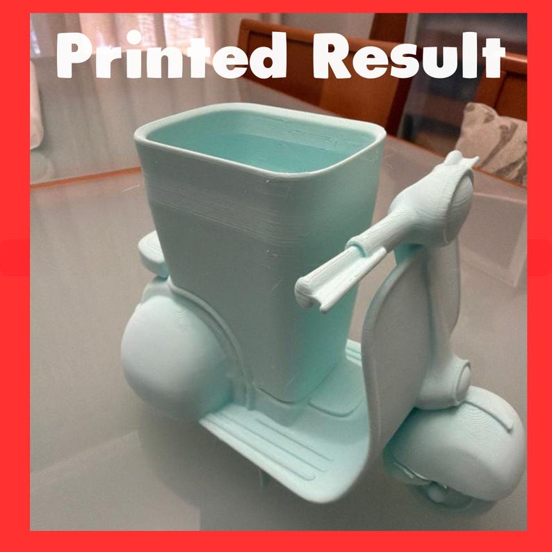 May include: A light mint green 3D printed desk organizer shaped like a vintage scooter. The object features a rectangular storage compartment integrated into the body of the scooter, with handlebars and a front wheel visible at the front.