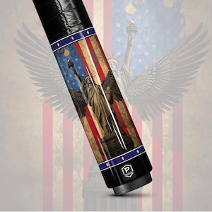 May include: A black and silver pool cue with a design featuring the Statue of Liberty with wings, set against a backdrop of the American flag. The cue has a black grip and a logo at the base.