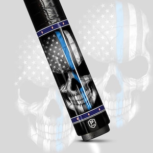 May include: A black and silver cue stick featuring a skull design with an American flag and a blue line. The cue stick has a black grip and a silver tip. The design includes the text "PRO CUE".