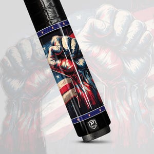 May include: A black and silver pool cue with a graphic of a clenched fist over an American flag design. The cue features a black leather grip and a logo at the base.
