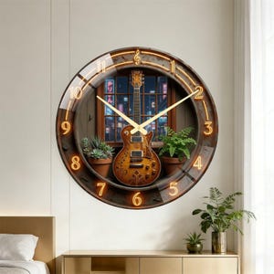 May include: A round wall clock featuring a guitar design. The clock face has a brown frame with a neon-style light around the edge and gold-colored hands. The background shows a window with plants and a city view.