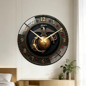 May include: A round wall clock with a dark green and gold design. The clock features a detailed emblem with an eagle, globe, and anchor. The clock hands and numerals are gold. The clock is approximately 12 inches in diameter.