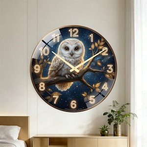 May include: A round wall clock featuring a detailed illustration of an owl perched on a branch. The clock face has gold numerals and hands, set against a dark blue starry background. The clock is framed in a gold-colored metal.