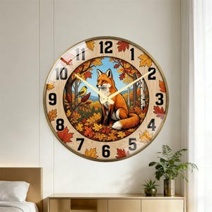 May include: A round wall clock with a gold-colored frame. The clock face features a fox in an autumn forest scene with a yellow bird, surrounded by leaves and the numbers 1 through 12. The clock hands are gold.
