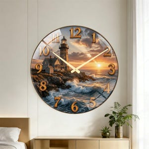 May include: Round wall clock featuring a coastal lighthouse scene with a sunset backdrop. The clock has gold-colored numerals and hands, and a glass cover. The lighthouse is set on a rocky shore with waves crashing against the rocks.