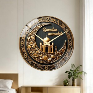 May include: A round wall clock with a black face featuring a gold crescent moon, floral carvings, and a mosque illustration. The text "Ramadan" and "mubarak" are in gold script. Gold numbers and clock hands are set against a dark background.