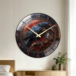May include: A round wall clock featuring a dark blue raven perched on a branch against a red background. The clock face displays gold hands, copper-colored numbers, and celestial constellation patterns. Two small mechanical gear sub-dials are visible.