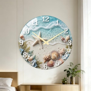 May include: Round wall clock with a beach scene design. The clock face features a starfish, seashells, and a sandy beach with ocean waves. The clock hands are gold, and the numbers are white.
