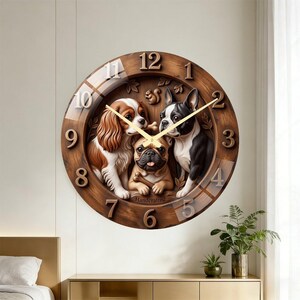 Könnte beinhalten: Eine runde Wanduhr mit einem dunklen Holzrahmen und erhabenen Ziffern von 1 bis 12. In der Mitte befindet sich ein Relief von drei Hunden: einem Cavalier King Charles Spaniel, einer Französischen Bulldogge und einem Boston Terrier. Goldene Zeiger.