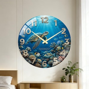 May include: A round wall clock featuring a vibrant underwater scene with a sea turtle swimming among coral reefs and tropical fish. The clock face displays large, metallic-colored numerals from 1 to 12 and thin, gold-toned hour and minute hands.
