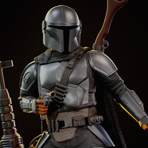 Puede incluir: Figura detallada de El Mandaloriano con armadura plateada, sosteniendo una pistola bl&aacute;ster. La figura tiene un casco, hombreras y un rifle marr&oacute;n sobre el hombro. La figura est&aacute; sobre un fondo oscuro.