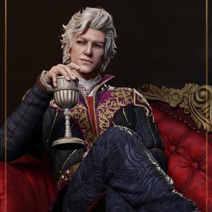 Könnte beinhalten: Detaillierte Statue einer Person mit weißem Haar, die eine schwarze und violette Jacke mit goldener Stickerei trägt und einen silbernen Kelch hält. Die Figur sitzt auf einem roten, verzierten Sofa. Die Statue hat ein königliches Aussehen.