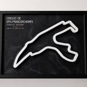 May include: A framed wall art piece featuring a white 3D outline of the Circuit de Spa-Francorchamps on a black topographic background. Text reads: CIRCUIT DE SPA-FRANCORCHAMPS, STAVELOT, BELGIUM, 7.004 KM, 19 TURNS, EST. 1921.