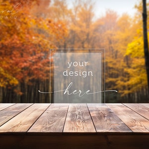 Könnte beinhalten: Eine Holztischplatte mit einem verschwommenen Hintergrund aus Herbstlaub. Der Text "your design here" befindet sich in einem transparenten Kasten auf dem Tisch.