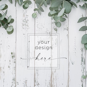 May include: Whitewashed wooden background with eucalyptus greenery framing a rectangle with the text "your design here".