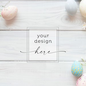 Puede incluir: Fondo de madera blanqueado con un marco que dice "tu diseño aquí". El fondo está decorado con huevos de Pascua de colores pastel y flores blancas.