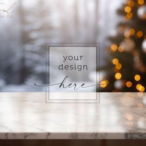 May include: A marble-patterned surface with the text "your design here" in a framed box. The background features a blurred winter scene and a Christmas tree with bokeh lights. The top left corner has the text "Feral Media Co."