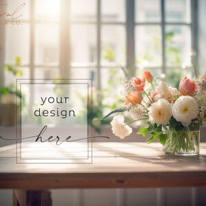 Op de afbeelding: Een boeket van perzikkleurige en witte bloemen in een glazen vaas op een houten tafel met een raam op de achtergrond. De tekst "your design here" staat in een kader op de tafel.