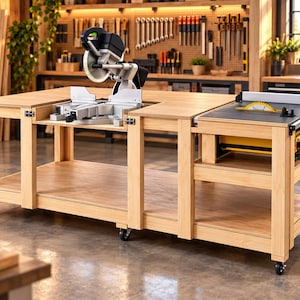 May include: A light-colored wooden workbench on wheels featuring a built-in miter saw in the center and a table saw integrated into the right side. The structure includes a lower shelf and a flat surface area for various woodworking tasks.