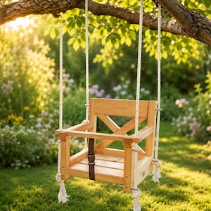 May include: A light-coloured wooden swing with a square seat, a backrest featuring an X-shaped support, and a front safety bar. The swing is suspended by thick white twisted ropes and includes a brown adjustable strap attached to the seat base.