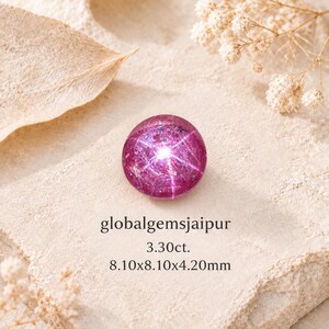 May include: A round, deep pink star ruby gemstone featuring a distinct six-rayed star effect. The stone is labeled with the text globalgemsjaipur, 3.30ct., and 8.10x8.10x4.20mm. The gemstone displays a polished, cabochon surface with internal inclusions.