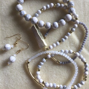 May include: Set of white marble and gold bead bracelets with a gold bar pendant and matching white marble earrings.
