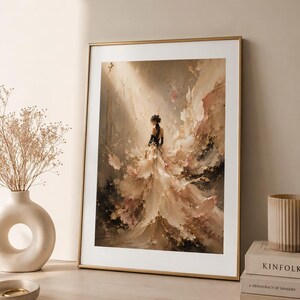 May include: An abstract painting in a gold frame depicts a figure in a flowing gown. The artwork uses a palette of beige, brown, and black, with a focus on texture and light. The framed art is displayed on a wooden surface.