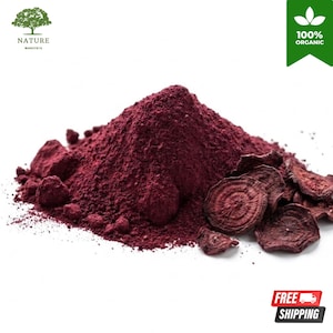 Könnte beinhalten: Ein Haufen tiefviolettes Rote-Bete-Pulver mit mehreren getrockneten, in Scheiben geschnittenen Rote-Bete-Chips an der Seite. Das Bild enthält ein grünes Logo mit einem Baum und dem Text NATURE monstera sowie ein grünes Banner mit 100% ORGANIC.