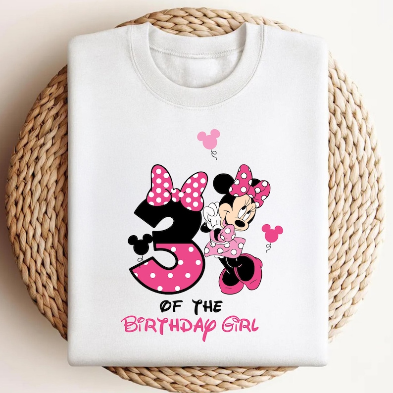 Pu&ograve; includere: Felpa bianca con grafica di Minnie Mouse. Il design include un grande numero 3 nero con pois rosa, Minnie Mouse e la scritta "OF THE BIRTHDAY GIRL" in rosa. Palloncini rosa a forma di orecchie di topo completano il design.