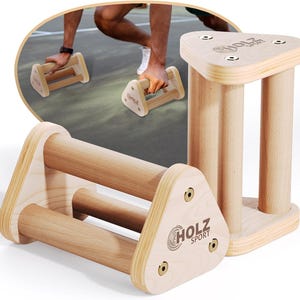 May include: Two light-colored wooden push-up bars with triangular side panels. Each bar features two horizontal cylindrical grips and the text HOLZ SPORT printed on the side. The design includes metal hardware securing the wooden components together.