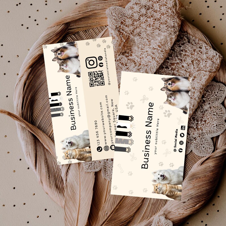 May include: Two rectangular business cards with a cream background featuring photos of a dog and cat, paw print patterns, and black text. The cards display Business Name, your subtitle here, contact details, social media icons, and a QR code.