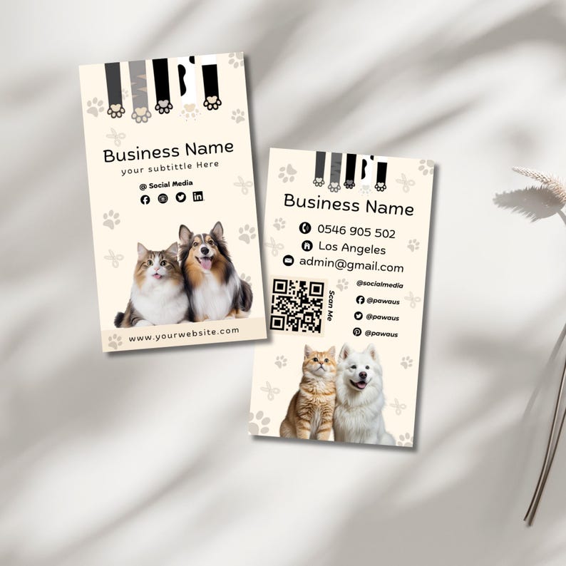 May include: Two rectangular business cards with a cream background featuring paw print patterns and animal paw graphics at the top. Each card displays Business Name, contact details, social media icons, a QR code, and photos of a cat and dog.
