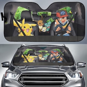 Puede incluir: Parasol de coche negro con un diseño de dibujos animados colorido. El diseño incluye personajes como Pikachu, Eevee y Ash de la serie animada. El parasol está diseñado para encajar en el parabrisas de un coche.