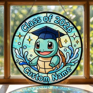 May include: Round stained glass window art featuring a cartoon turtle wearing a graduation cap. The text "Class of 2026" and "Custom Name" are displayed in a blue font. The turtle is surrounded by water and stars.