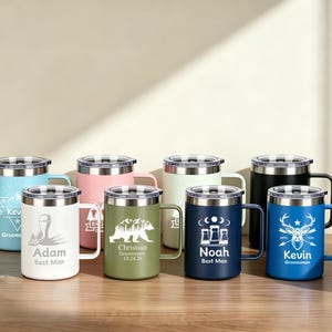 Puede incluir: Una colección de tazas de viaje aisladas en varios colores, cada una con tapa y asa plateadas. Las tazas están personalizadas con nombres y gráficos, incluyendo un oso, un ciervo y diseños geométricos. Las tazas están sobre una superficie de madera.
