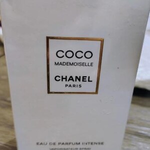 May include: White rectangular box with gold trim featuring the text "COCO MADEMOISELLE CHANEL PARIS". The box also indicates "EAU DE PARFUM INTENSE" and "3.4 FL. OZ". The box is for a fragrance product.