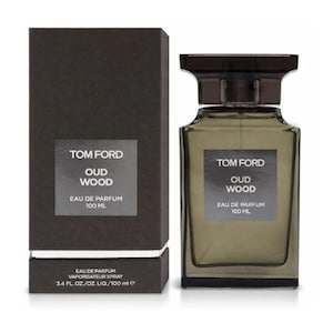 May include: A Tom Ford Oud Wood Eau de Parfum bottle and box set. The rectangular bottle is clear with a dark brown cap. The box is dark brown with white text that reads "Tom Ford Oud Wood Eau de Parfum 100 ML". The set includes 3.4 fl oz.