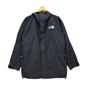 May include: Black hooded jacket with the white "The North Face" logo on the chest. The jacket has a button-up front, multiple pockets, and adjustable drawstrings. The jacket is hanging on a wooden hanger.