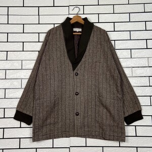 May include: Brown herringbone jacket with vertical stripes, a dark brown shawl collar, and three buttons. The jacket has two front pockets and dark brown cuffs. The brand name is visible on the collar.