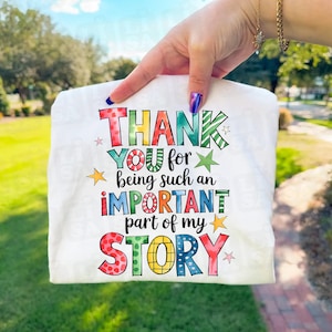 May include: White t-shirt featuring the text "THANK YOU for being such an IMPORTANT part of my STORY" in a vibrant, multi-coloured design. The text is accented with stars.