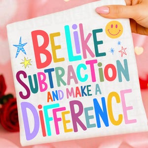 May include: A white square textile with the words "BE LIKE SUBTRACTION AND MAKE A DIFFERENCE" in colorful block letters. The design includes a smiley face, stars, and a starburst.