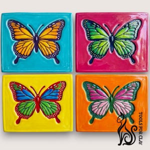 Puede incluir: Cuatro baldosas de cerámica coloridas, cada una con un diseño detallado de mariposa. Las mariposas están representadas en tonos vibrantes de amarillo, naranja, verde, azul y rosa, sobre fondos contrastantes. Las baldosas son cuadradas y parecen hechas a mano.