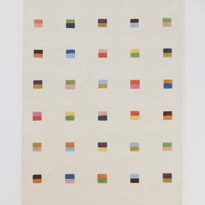 May include: Off-white rectangular rug featuring a repeating pattern of coloured squares. The squares are in various colours, including blue, pink, green, orange, and yellow. The rug has a simple, modern design.