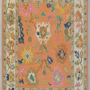 May include: A rectangular rug with a detailed floral pattern. The rug has a peach-coloured central field with colourful floral motifs in pink, blue, yellow, and green. A cream-coloured border frames the design, adding contrast and visual interest.