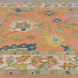 May include: A large, rectangular rug with an intricate floral pattern. The rug features a peach-coloured centre with various floral designs in shades of yellow, blue, pink, and green. The border is a cream colour with more floral motifs.